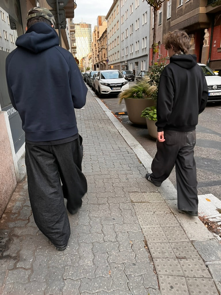 Two people walking down a Bratislava street from behind, wide trousers worn low